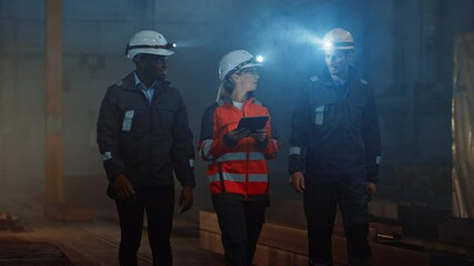Aufkleber - Three Diverse Multicultural Heavy Industry Engineers and Workers in Uniform Walk in Dark Steel Factory Using Flashlights on Their Hard Hats. Female Industrial Contractor is Using a Tablet Computer.