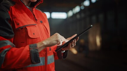 Wall Mural - Close Up on Hands of a Professional Female Heavy Industry Engineer Wearing Safety Uniform and Using Tablet Computer. Industrial Specialist Standing in a Metal Construction Manufacture.