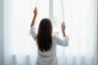 © surachetkhamsuk - Young Asian woman opening the curtain in the morning after wake up