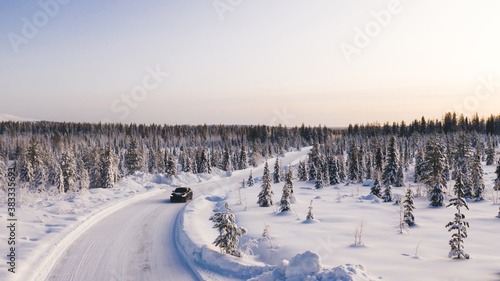 Fotomural Bird’s eye view of vehicle car moving on rural road having good insurance for winter weather, aerial view of suv automobile driving in scenery area surrounded by coniferous forest