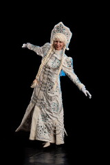 Snow Maiden in a white fur coat and kokoshnik poses on a black background