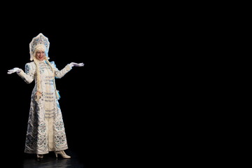 Snow Maiden in a white fur coat, kokoshnik and long hair braids holding a Santa Claus gift, posing on a black background