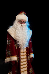 Santa Claus in a red fur coat, with a white beard posing on a black background