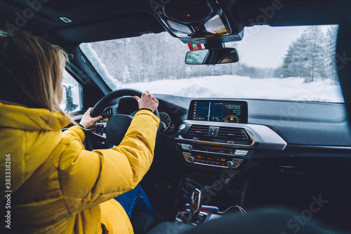 Professional female driver explore destination by car having good winter wheel for safe travel, woman traveler driving automobile on wildwood nature landscape