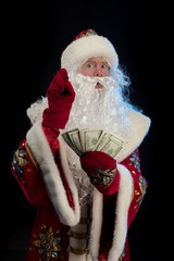 Santa Claus in a red fur coat, with a white beard posing on a black background