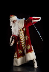 Santa Claus in a red fur coat, with a white beard with a baseball bat in his hands, posing on a black background