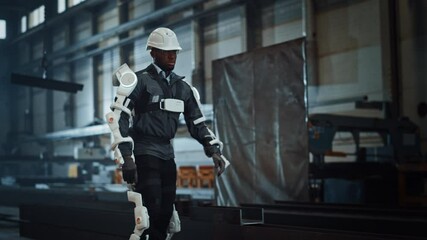 Poster - Black African American Engineer is Testing a Futuristic Bionic Exoskeleton and Picking Up Metal Objects in a Heavy Steel Industry Factory. Contractor is Heavy Lifting Steel Parts in a Powered Shell.