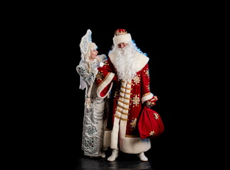 Wall Mural - Santa Claus in a red suit and the Snow Maiden in a white fur coat posing against a black background