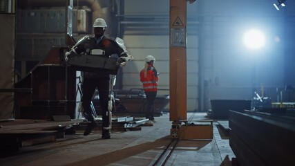 Fototapete - Black African American Engineer is Testing a Futuristic Bionic Exoskeleton and Picking Up Metal Objects in a Heavy Steel Industry Factory. Contractor is Heavy Lifting Steel Parts in a Powered Shell.