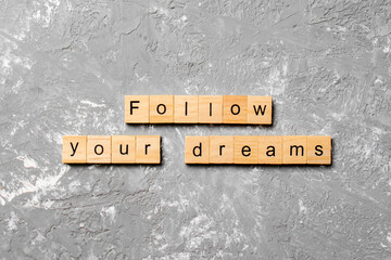 Follow your dreams word written on wood block. Follow your dreams text on cement table for your desing, Top view concept