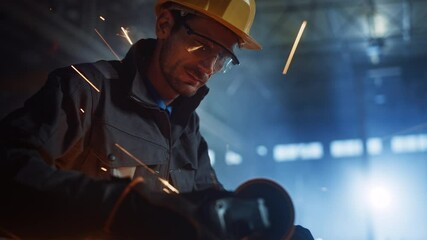 Wall Mural - Heavy Industry Engineering Factory Interior with Industrial Worker Using Angle Grinder and Cutting a Metal Tube. Contractor in Safety Uniform and Hard Hat Manufacturing Metal Structures.