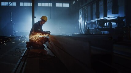 Wall Mural - Heavy Industry Engineering Factory Interior with Industrial Worker Using Angle Grinder and Cutting a Metal Tube. Contractor in Safety Uniform and Hard Hat Manufacturing Metal Structures.