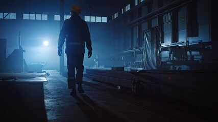 Wall Mural - Professional Heavy Industry Engineer/Worker Wearing Uniform, Glasses and Hard Hat in a Steel Factory. Industrial Specialist Walking Away in a Dark Metal Construction Manufacture.