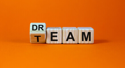 Turned cubes and changed the word 'dream' to 'team'. Beautiful orange background. Business concept, copy space.