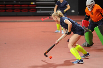 Young woman player in attack at indoor hockey match