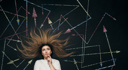 young woman making decision with arrows written on school blackboard above head, brainstorming concept, girl finding solution in tangled ways top view