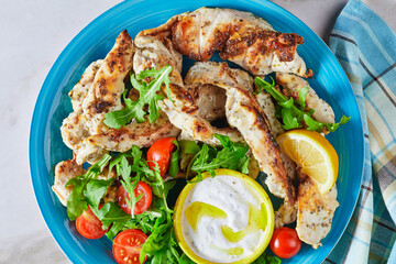 Grilled chicken with arugula salad on a blue plate