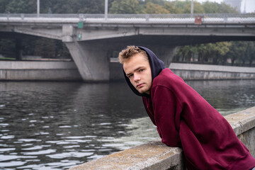 Wall Mural - sad lonely teenager in hoodie by the river