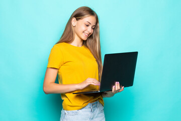 Young woman working on laptop posing isolated on turquoise background