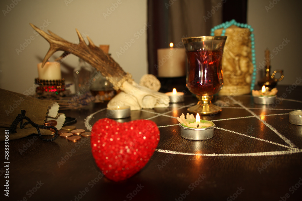 in a dark room candles are burning on a round esoteric table, animal ...