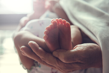 Wall Mural - parent is holding small infant. baby's foot is in focus.