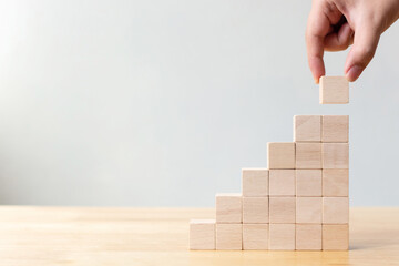 Hand arranging wood block stacking as step stair on wooden table. Business concept for growth success process. Copy space