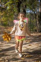 Happy little young girl with a bouquet of yellow and orange leaves resting and walking in nature in the autumn forest  near the lake in Moscow region of Russia with yellow and orange autumn leaves