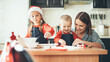 © Strelciuc - Happy caucasian family preparing cookies for christmas at home waring santa clothes and hat