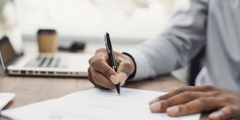 Young man signing an official document, male hand holding pen putting signature at paper contract agreement. Business, lawyer, finance, notary, trading, loan, accounting concept