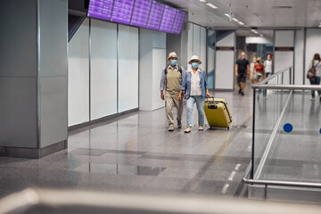 Wall Mural - Elderly tourist couple with luggage walking ahead