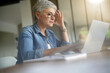 © goodluz - portrait of a beautiful 55 year old woman with white hair working from home