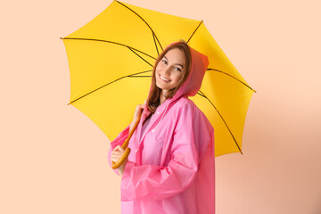 Wall Mural - Beautiful young woman in raincoat and with umbrella on color background