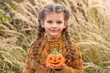 Wall Mural - A little girl with a pumpkin in her hands.