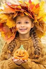 Wall Mural - A child with a wreath on his head and a pumpkin in his hands for Halloween.
