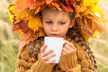 Wall Mural - A little girl drinks tea on an autumn day.