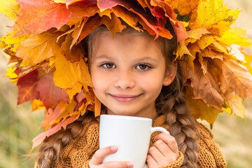 Wall Mural - On a bright autumn day, a little girl drinks a hot drink.