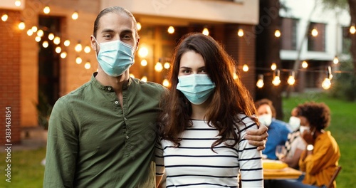 Cuadros en Lienzo Portrait of Caucasian young couple in medical masks hugging in yard at picnic