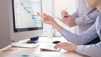 project management team updating planning schedule with gantt chart on computer at the office to com