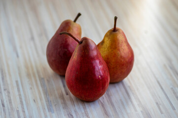 Three pears edible fruits, tasty ripened red yellow fruit on wooden background