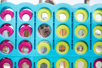 Young girl child face playing large oversize fun connect four game pink blue green circles strategy thinking piece puzzle