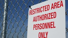 Restricted Area, Authorized Personnel Only Sign In USA. Red Letters, Keep Off Warning On Metal Fence, United States Border Symbol. No Trespassing Notice Means Violators Will Be Prosecuted By US Law.