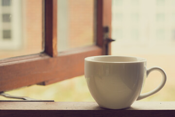 White coffee cup of hot tea or coffee on vintage wooden  with window background