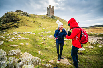daughter looking at mother on winter walk overlooked by ruined castle