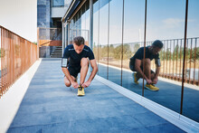 Sportsman Tying His Shoelaces. He Is Wearing Yellow Sneakers.