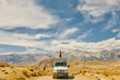 © Cavan Images - Young man on roof of camper van with open arms in northern California.