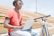 © Cavan Images - Ethnic guy using laptop near bicycle