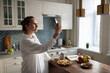 © Cavan Images - Businesswoman using smartphone for communication in kitchen