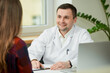 © Roman Tyukin - A caucasian doctor in a white lab coat is rejoicing in the success of the healing of a female patient in a hospital. A woman with long hair at an appointment in a doctor's office.