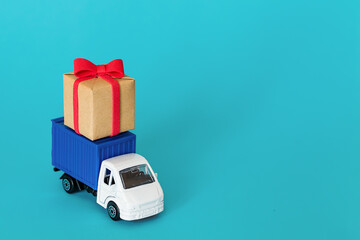 car delivering gift box for Valentine's day on blue background. Cargo transportation, delivery service. Transport company. Infrastructure and logistics. Unloading cardboard box. Place for text