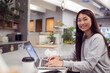 © Monkey Business - Businesswoman Working On Laptop In Kitchen Area Of Modern Office